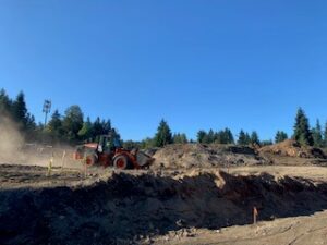 A bulldozer is working on a dirt road for a new home expansion project.