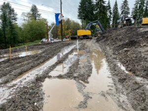 A muddy road with construction equipment working regardless of weather obstacles.