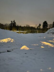 A snowy field illuminated by a light.