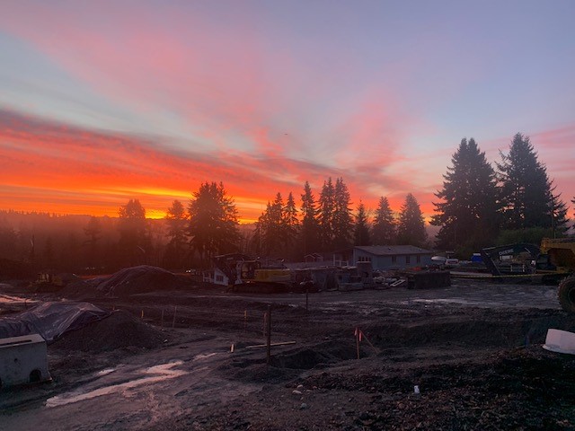 A sunset over a construction site with a bulldozer in the background captures the essence of springtime.