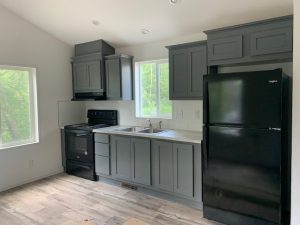 A kitchen with new gray cabinets and a black stove.