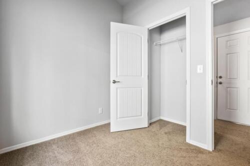 An empty room with a closet and a door.