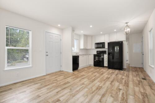 A kitchen with hardwood floors and white appliances.