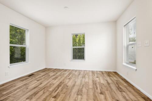 An empty room with hardwood floors and windows.