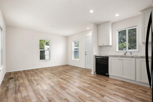 An empty kitchen with wood floors and windows.