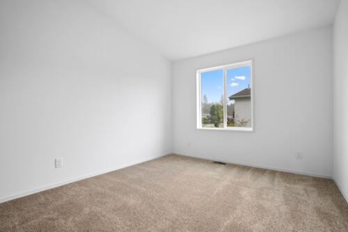 An empty room with white walls and tan carpet.