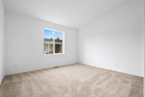 Empty room with white walls and tan carpet.
