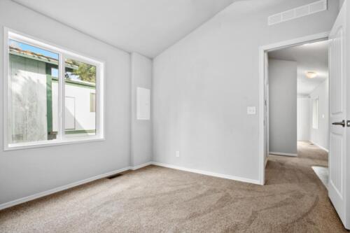 An empty room with beige carpet and white walls.