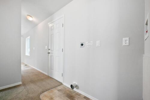 A hallway with white walls and wood floors.