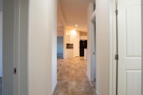 A hallway in a home with white walls and wood floors.