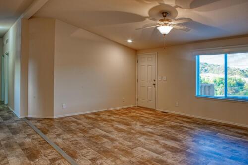An empty living room with hardwood floors and a ceiling fan.