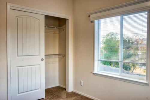 An empty room with a closet and a window.