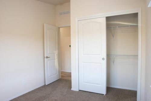 An empty room with a closet and closet doors.