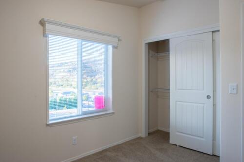 A bedroom with a closet and a window.